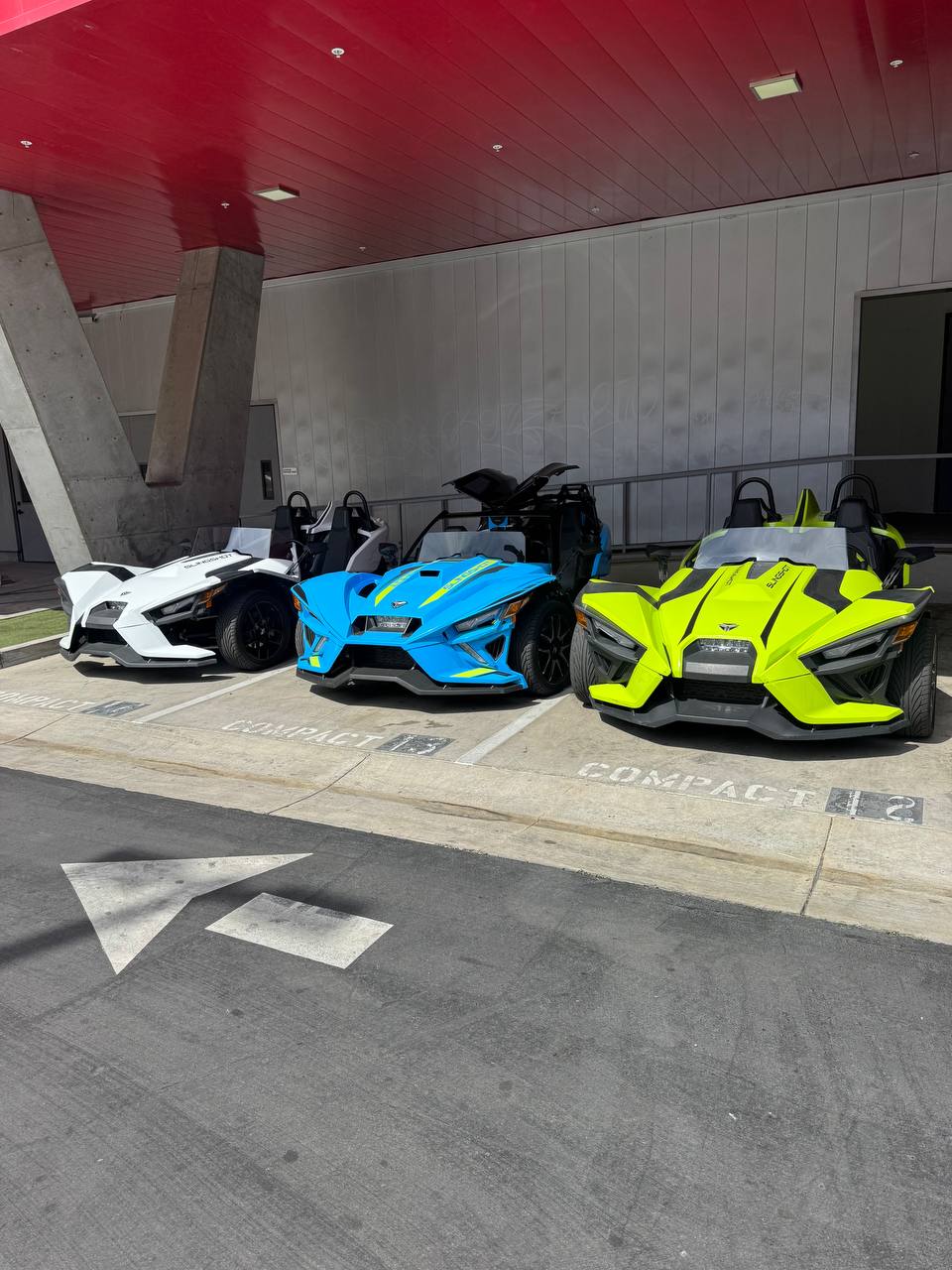 The SLY Slingshot fleet — white, electric blue, and neon yellow Polaris Slingshots